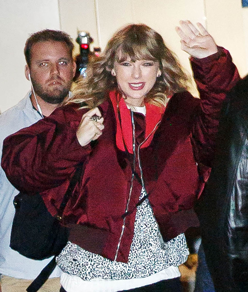 Taylor Swift waves at her fans while wearing a snake ring on her right middle finger at her popup store in New York